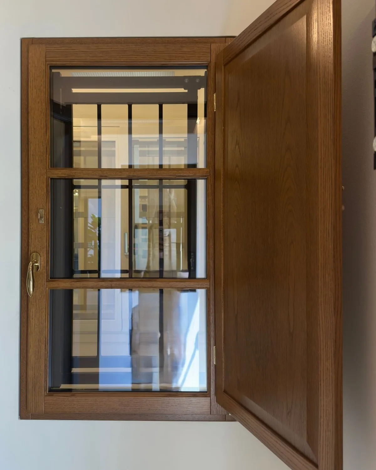 Finestra in rovere lamellare con inglesina e anta interna in legno aperta, esposta in showroom