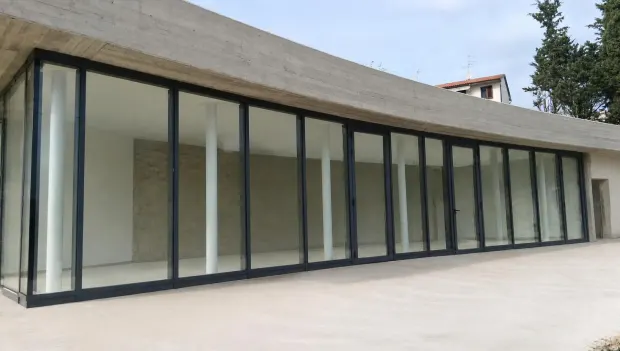 Vetrata continua a tutta altezza sul fronte rettilineo dell'edificio, profili in alluminio scuro