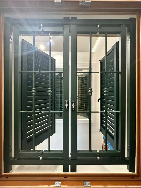 Finestra con grata di sicurezza e persiane verdi aperte, controtelaio in legno