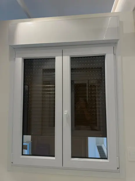 Monoblocco in PVC bianco con cassonetto integrato sopra una finestra a due ante